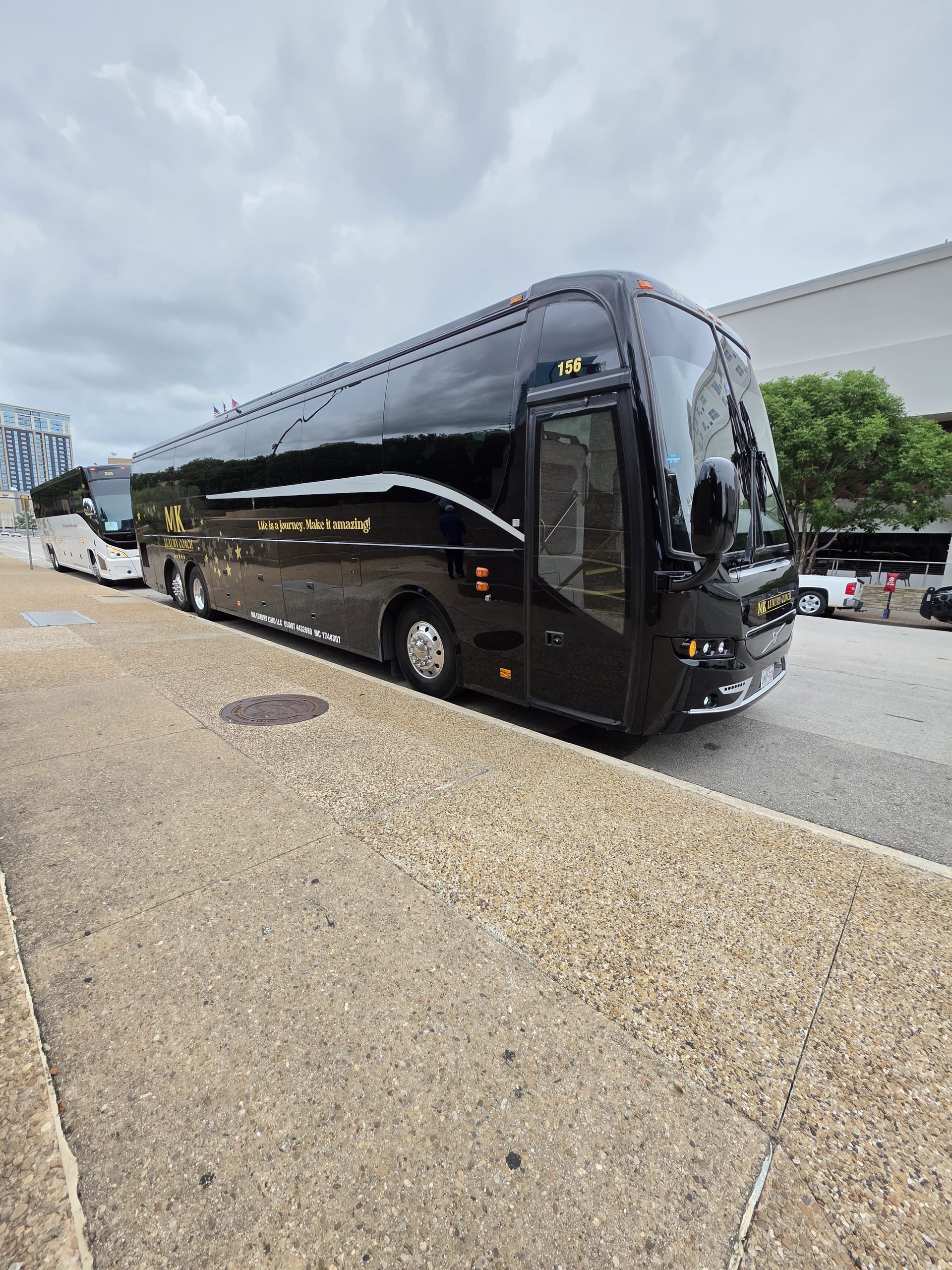 Black MK Luxury Coach motor coach with gold MK lettering parked downtown