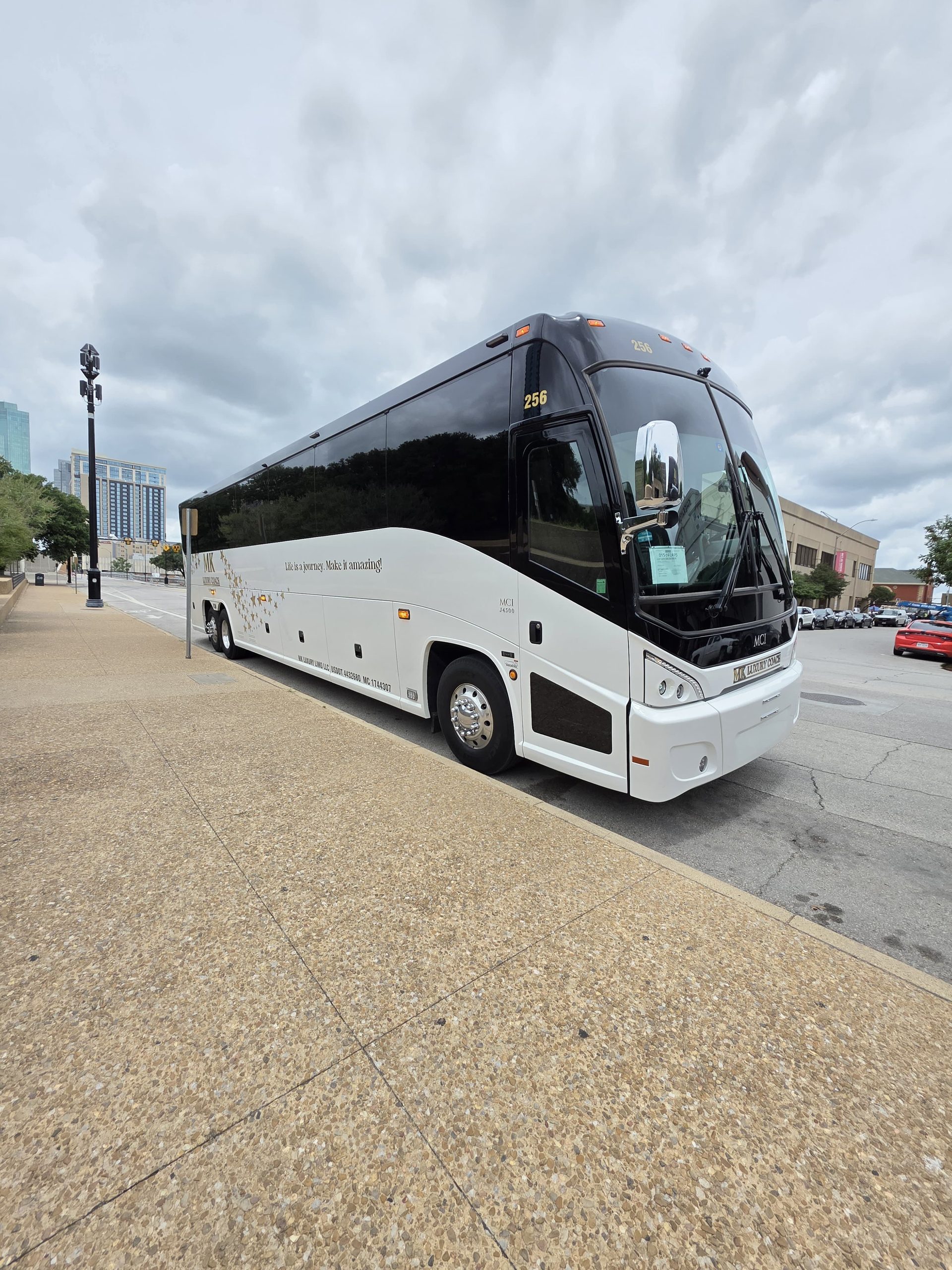 White MK Luxury Coach MCI J4500 motor coach at a downtown Dallas venue