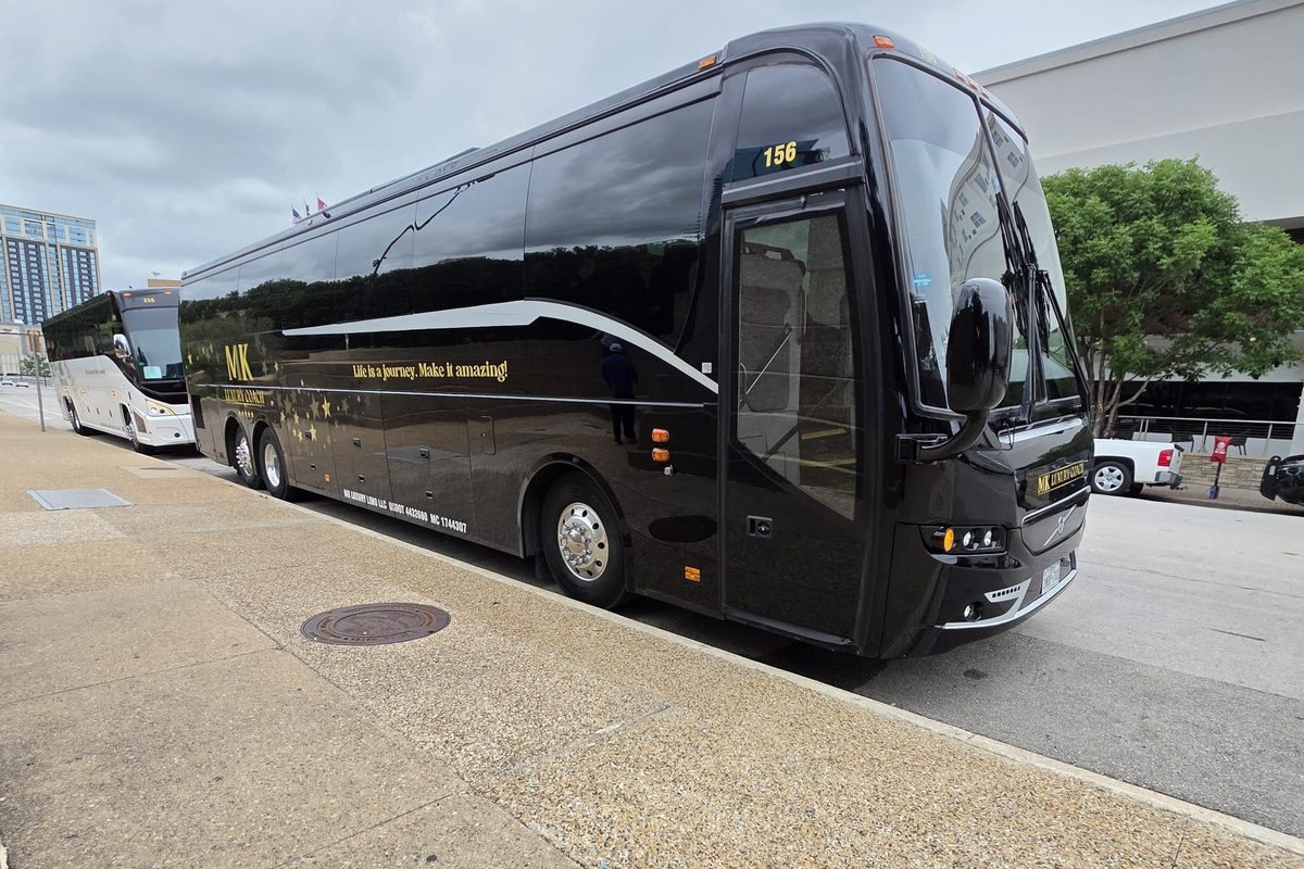 MK Luxury Coach black motor coach exterior with gold MK lettering, parked in downtown Dallas